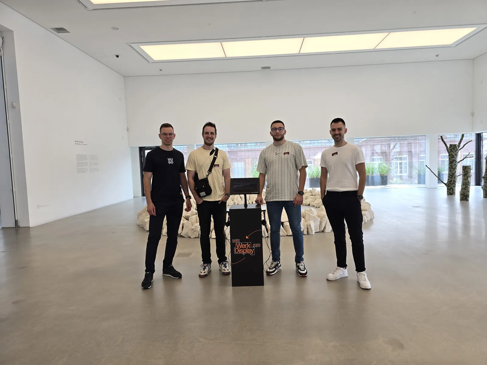 Four members of the team standing around a black Werk zum Display kiosk in the gallery.