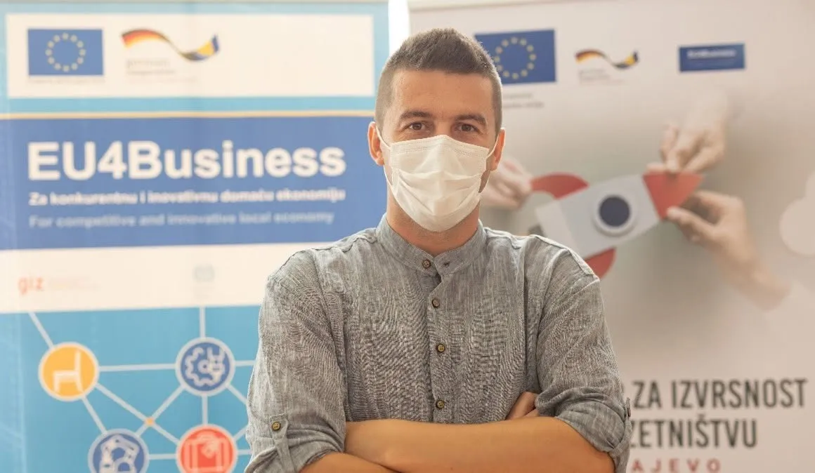 Amer Skrobo standing with his arms crossed, wearing a face mask, in front of EU4Business and Sarajevo Centre for Entrepreneurship Excellence banners.
